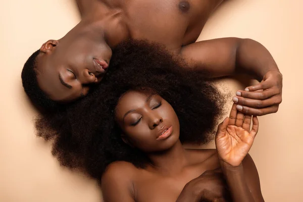 Vista aerea di sexy coppia africana americana nuda sdraiata con gli occhi chiusi sul beige — Foto stock