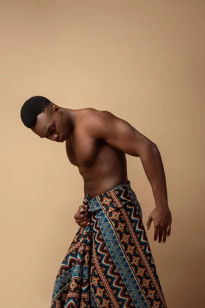 Sexy nudo tribale afro uomo coperto in coperta posa su beige — Foto stock