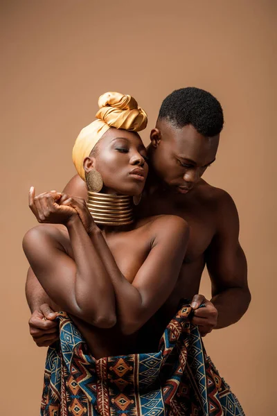 Sexy naked tribal afro woman covered in blanket posing near man isolated on beige — Stock Photo