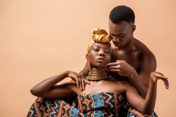 Sexy naked tribal afro woman covered in blanket posing near man isolated on beige — Stock Photo