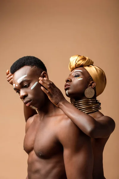Sexy desnudo tribal afro pareja posando en beige - foto de stock