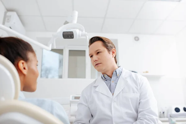 Enfoque selectivo del dentista mirando al paciente afroamericano - foto de stock