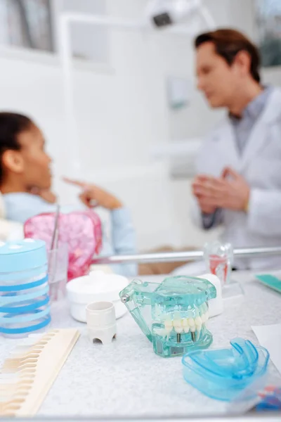 Foyer sélectif du modèle de dents et des dispositifs de retenue sur la surface près du dentiste et de la femme afro-américaine — Photo de stock