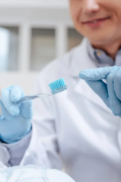 Selective focus of dentist pointing with finger at toothbrush — Stock Photo