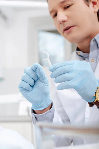 Селективный фокус стоматолога в латексных перчатках с зубной нитью — стоковое фото