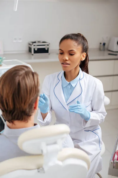 Selective focus of attractive african american dentist gesturing near patient — Stock Photo
