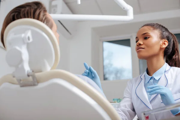 Selektiver Fokus des attraktiven afrikanisch-amerikanischen Zahnarztes, der mit dem Finger auf den Patienten zeigt — Stockfoto