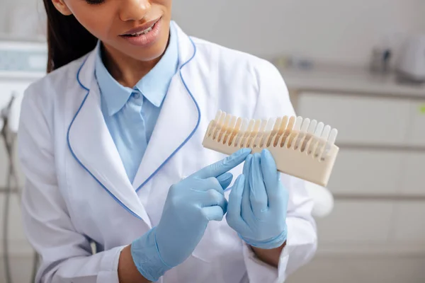 Cropped view of african american dentist pointing with finger at teeth palette — Stock Photo