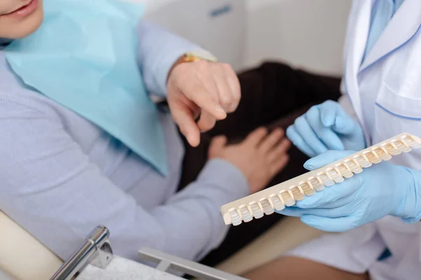 Cropped view of man pointing with finger at teeth palette near dentist — Stock Photo