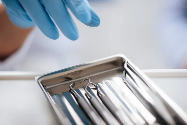 Vista ritagliata del noleggiatore in guanto di lattice che raggiunge per strumenti dentali inossidabili — Stock Photo