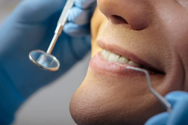 Vista cortada do dentista em luvas de látex segurando instrumentos dentários perto de homem feliz — Fotografia de Stock