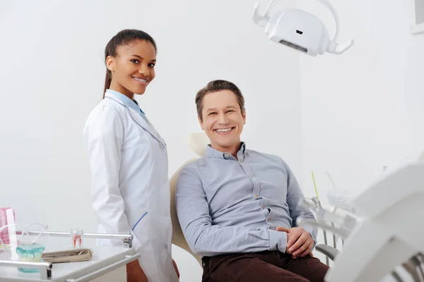 Messa a fuoco selettiva di felice paziente sorridente con allegro dentista africano americano in apparecchio — Foto stock