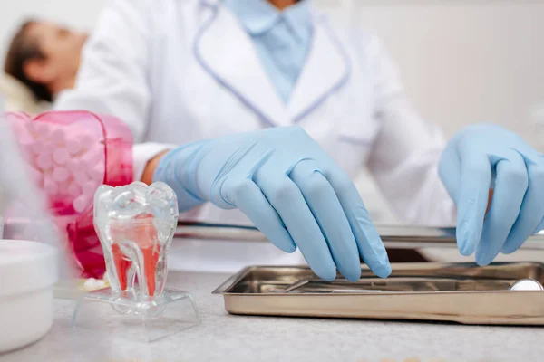 Visão recortada do dentista em luvas de látex tocando instrumentos dentários inoxidáveis — Fotografia de Stock