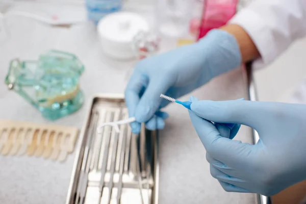 Vista recortada del dentista en guantes de látex con cepillo de limpieza interdental - foto de stock