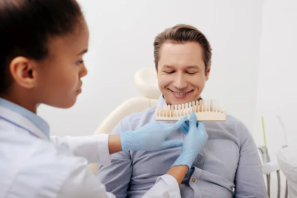 Selective focus of african american dentist holding teeth palette near happy patient in clinic — Stock Photo