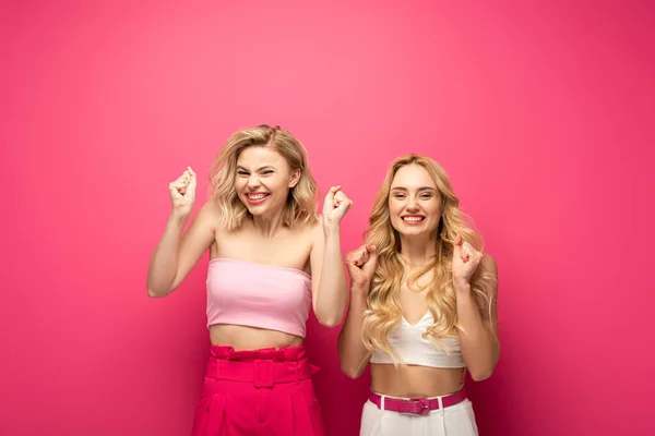 Glückliche blonde Frauen zeigen Yah-Geste auf rosa Hintergrund — Stockfoto