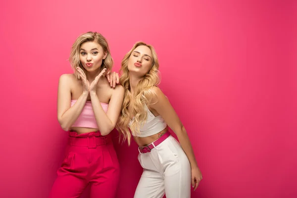 Красивые блондинки дуют воздушный поцелуй на розовом фоне — стоковое фото