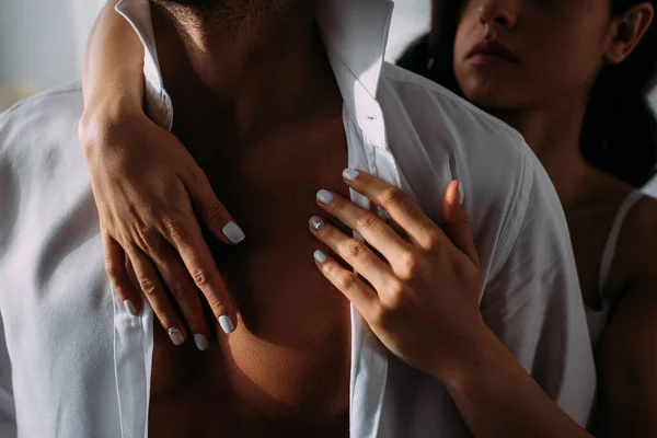 Cropped view of woman hugging businessman from behind in bedroom — Stock Photo