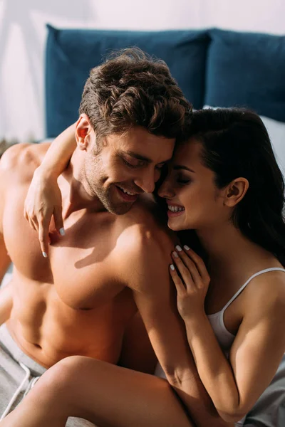 Счастливые парень и девушка обнимаются и улыбаются в спальне — стоковое фото