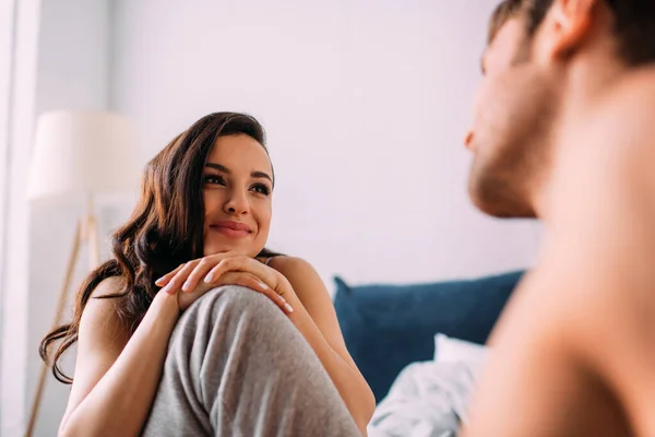 Selektiver Fokus der schönen Frau, die sich auf das männliche Knie stützt und ihren Freund im Schlafzimmer ansieht — Stockfoto