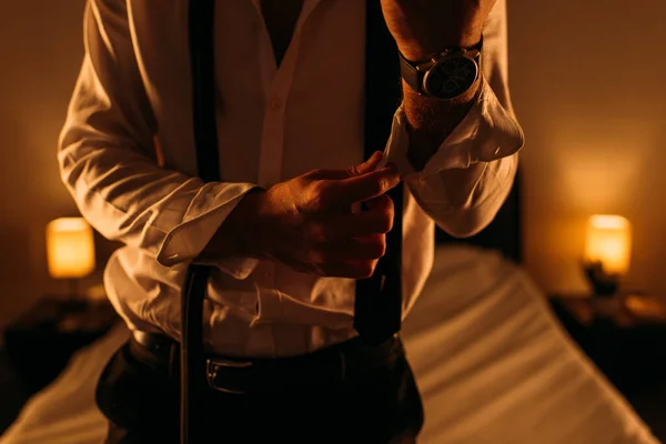 Обрезанный вид бизнесмена расстегивающего рукав в спальне — стоковое фото
