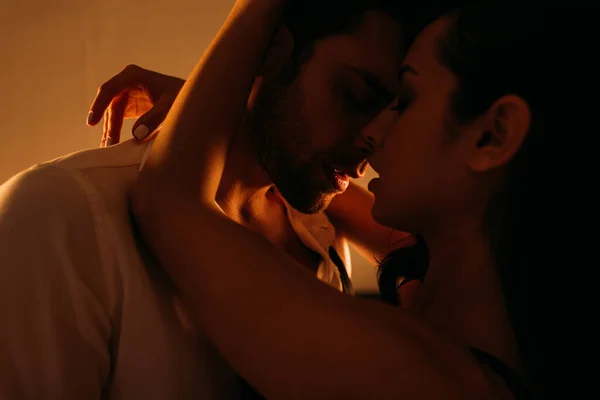 Femme passionnée embrassant homme d'affaires avec les yeux fermés dans la chambre — Photo de stock