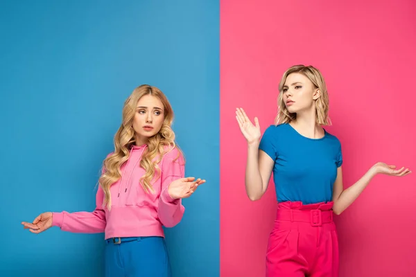 Chicas rubias confusas mostrando gesto de encogimiento de hombros sobre fondo rosa y azul - foto de stock