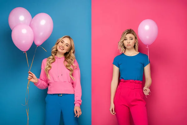 Smiling and sad blonde girls holding balloons on blue and pink background — Stock Photo