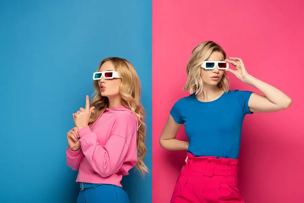 Attractive blonde sisters in 3d glasses on blue and pink background — Stock Photo