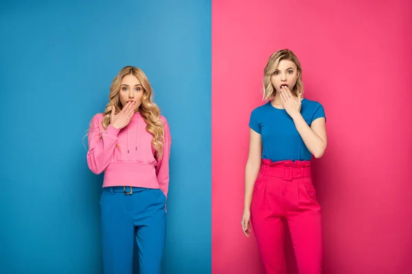 Shocked blonde girls looking at camera on pink and blue background — Stock Photo