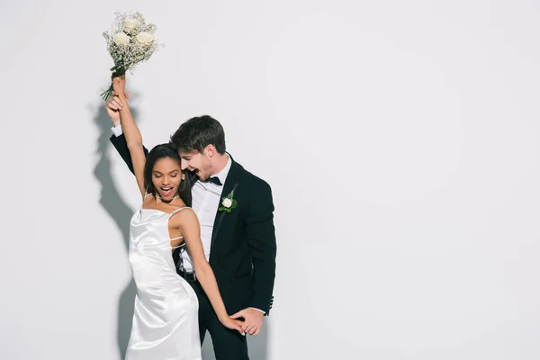 Feliz, elegante interracial recém-casados dançando no fundo branco — Fotografia de Stock