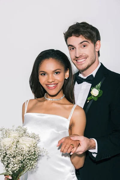 Fröhliche Bräutigam zeigt Hochzeit an der Hand der schönen afrikanisch-amerikanischen Braut auf weißem Hintergrund — Stockfoto