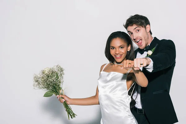 Heureux interracial jeunes mariés montrant des alliances sur leurs mains sur fond blanc — Photo de stock
