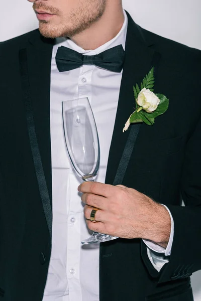 Partial view of bridegroom holding champagne glass isolated on white — Stock Photo