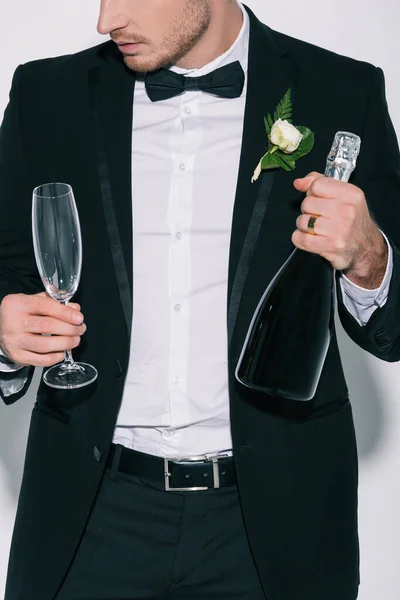 Vue recadrée du marié tenant verre de champagne et bouteille sur fond blanc — Photo de stock