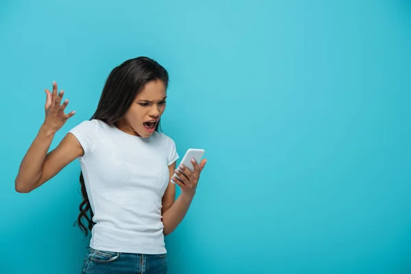 Arrabbiato africano americano ragazza urlando durante la videochiamata su smartphone isolato su blu — Foto stock