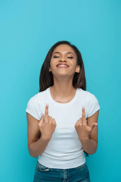 Sonriente afroamericana chica apuntando a los frenos dentales en sus dientes aislados en azul - foto de stock