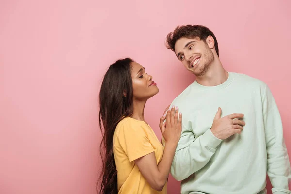 African american girl with asking face expression touching shoulder of smiling boyfriend on pink background — Stock Photo