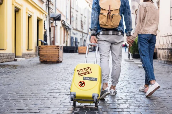 Cropped view of couple walking with travel bag on street, quarantine illustration — Stock Photo