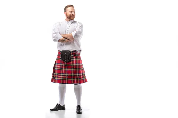 Посмішка шотландського рудого чоловіка в червоному кілті з перехрещеними руками на білому тлі — стокове фото