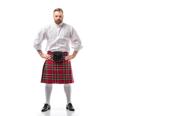 Grave escocês ruiva homem em kilt vermelho com as mãos em quadris no fundo branco — Fotografia de Stock
