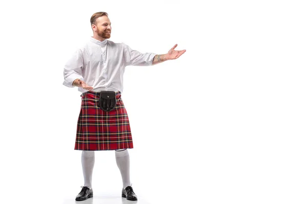 Smiling Scottish redhead man in red kilt gesturing on white background — Stock Photo