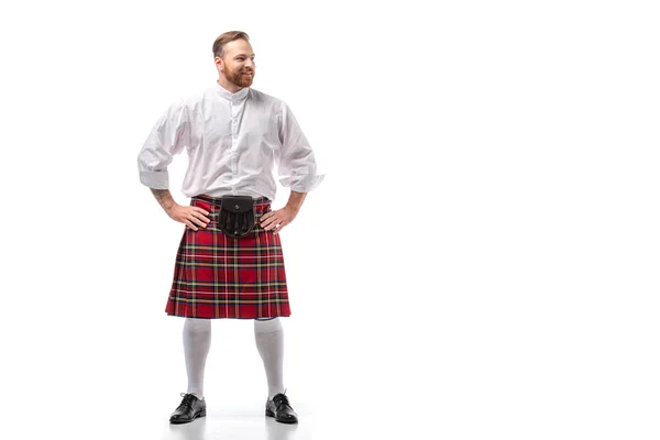 Homme rousse écossais souriant en kilt rouge avec les mains sur les hanches sur fond blanc — Photo de stock