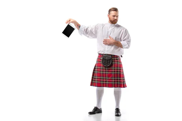 Homme rousse écossais mécontent en kilt rouge avec tablette numérique sur fond blanc — Photo de stock