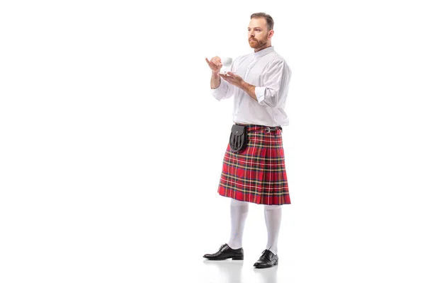 Escocês ruiva homem no vermelho kilt beber café no branco fundo — Fotografia de Stock