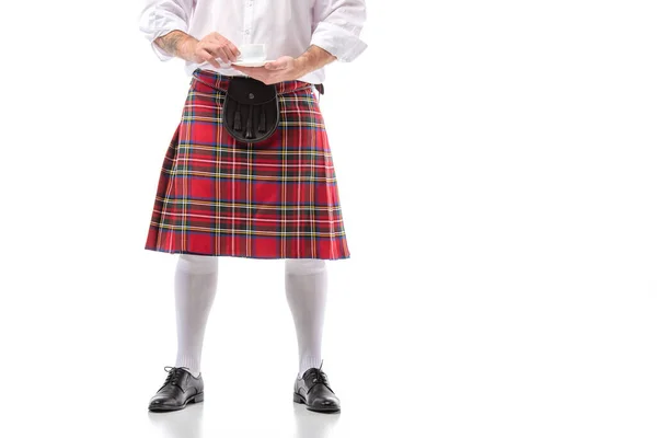 Ausgeschnittene Ansicht eines Schotten in rotem Kilt und Kniestrümpfen mit Kaffee auf weißem Hintergrund — Stockfoto