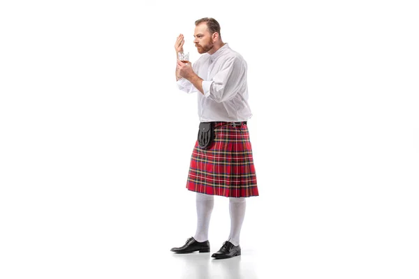 Scottish redhead man in red kilt smelling whiskey on white — Stock Photo