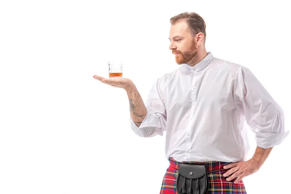 Scozzese rossa uomo in kilt rosso con whisky in vetro a portata di mano isolato su bianco — Foto stock