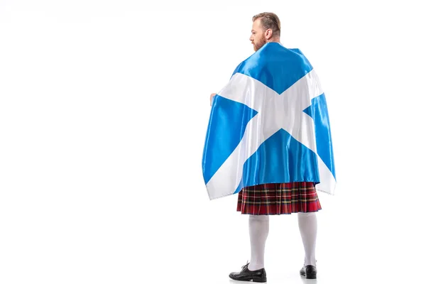 Visão traseira do homem ruivo escocês em kilt vermelho com bandeira da Escócia no fundo branco — Fotografia de Stock