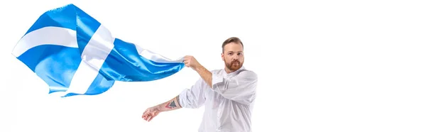 Шотландський рудий чоловік з прапором Шотландії ізольований на білому, панорамному врожаї — стокове фото